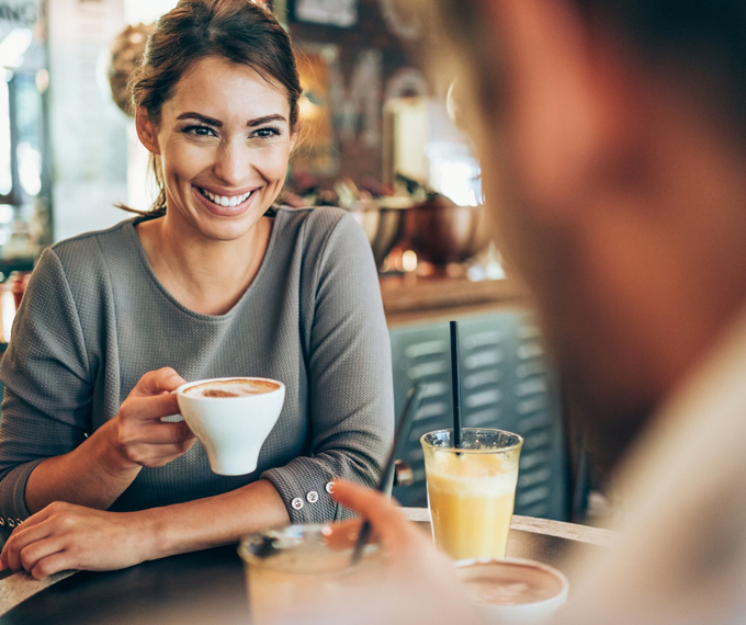 A woman with a perfect smile enjoying a coffee with a friend, showing off her beautiful teeth after a cosmetic dentistry treatment.